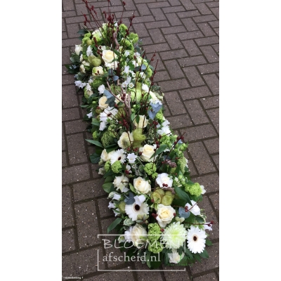 Kistbedekking van groene en witte bloemen
